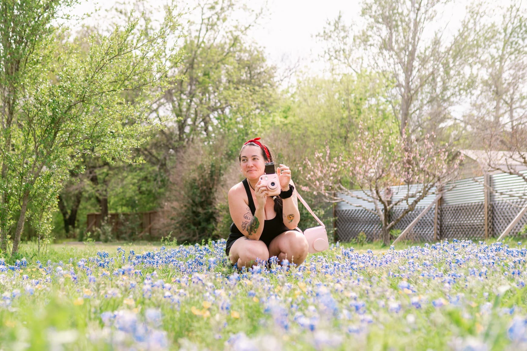 Person with a camera sitting in a flower field.