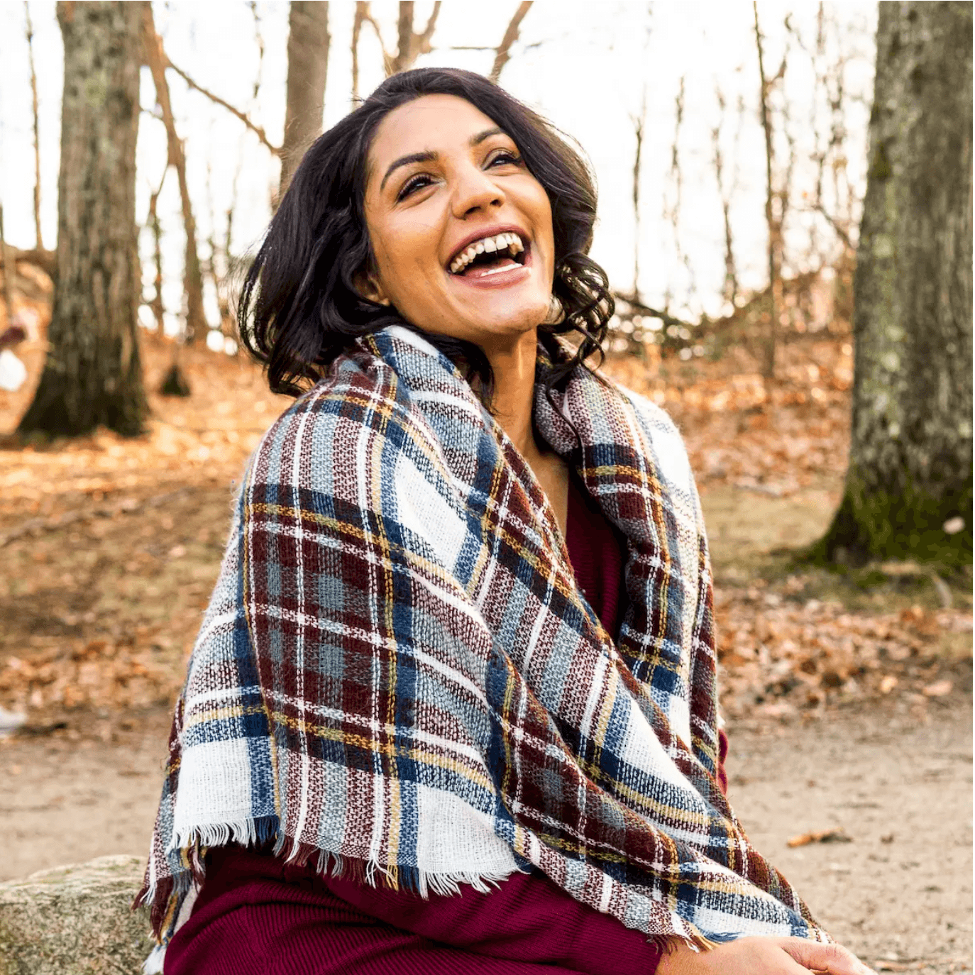 Woman laughing wrapped in a plaid blanket scarf outdoors in a park during free professional dating profile photo session with Shoott in Houston