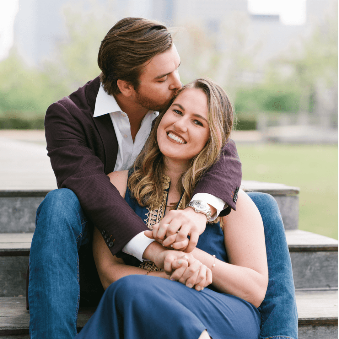 A man kissing a woman on the cheek while sitting on wooden steps.