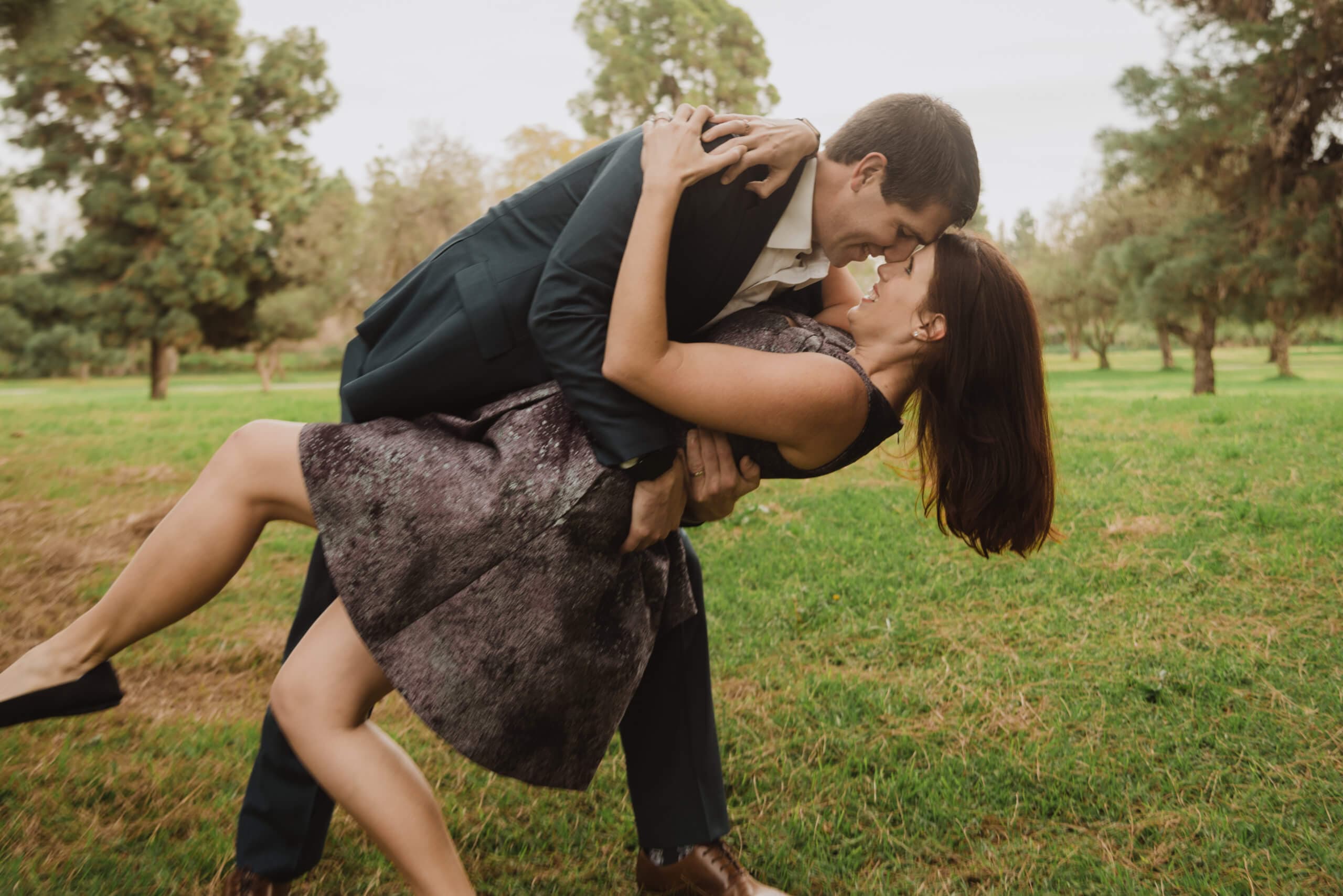 Man dipping a woman in a romantic dance move on a grass field