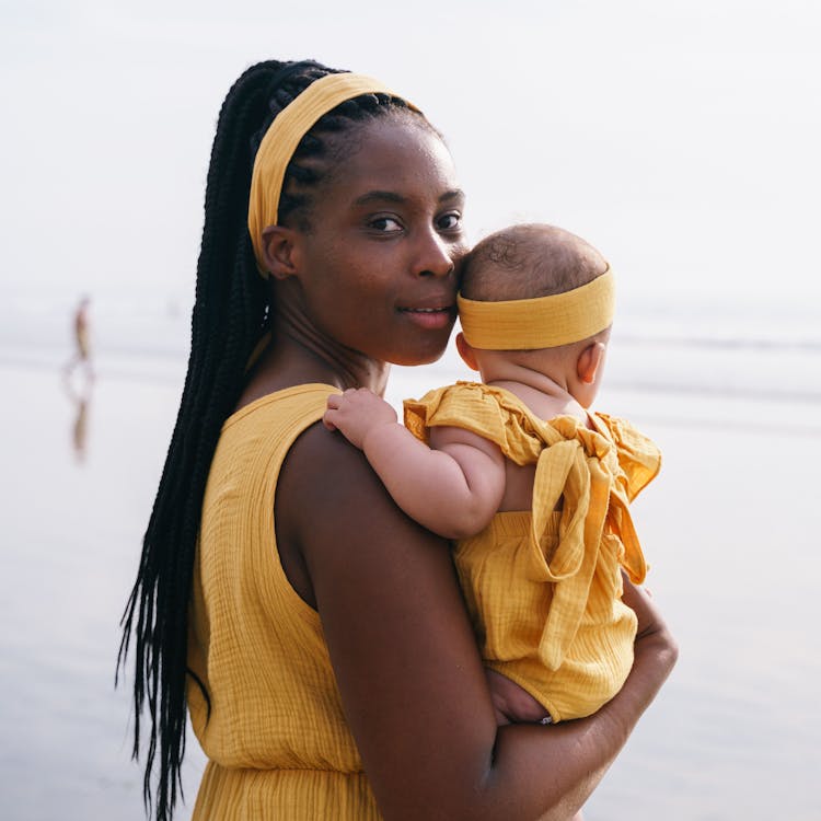 Mother and baby in matching yellow outfits pose on the beach for their free outdoor photoshoot