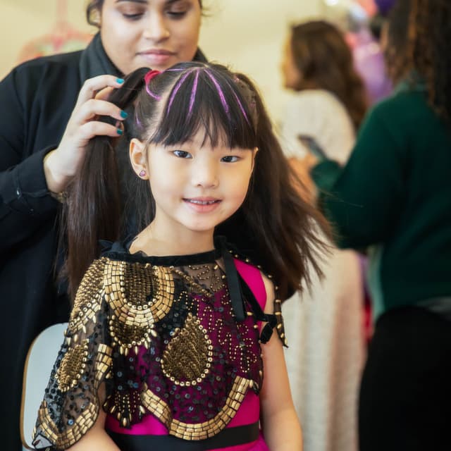 Young girl getting her hair styled with a bright pink streak