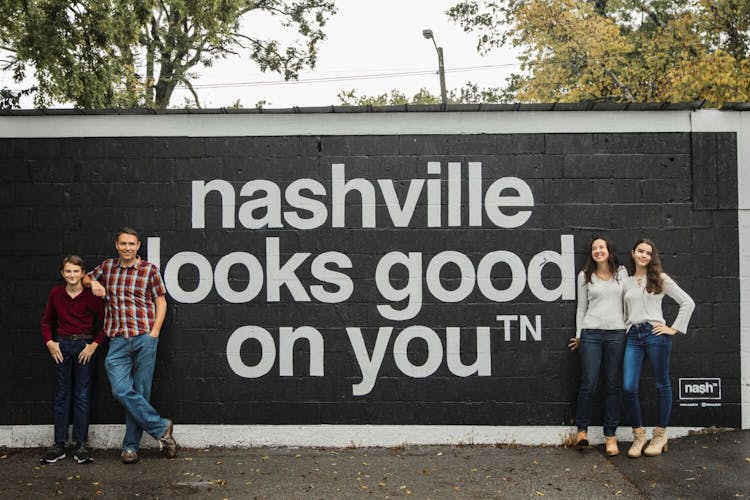 Family of four posing in front of a mural that says 'Nashville looks good on you' in Nashville, TN