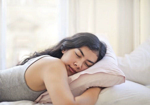 Woman resting on a pillow with eyes closed.