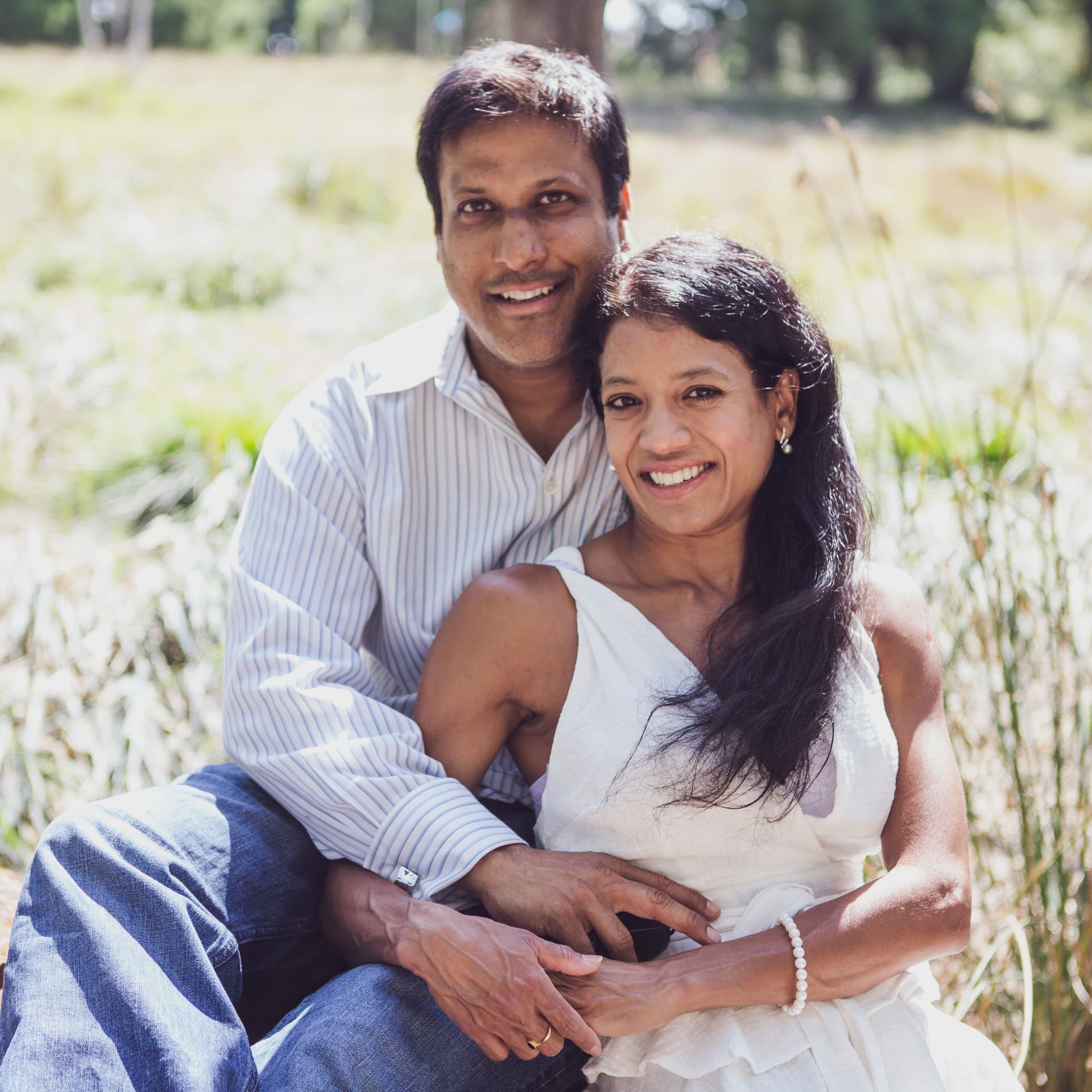 Smiling family in matching blue outfits pose for free outdoor park photoshoot