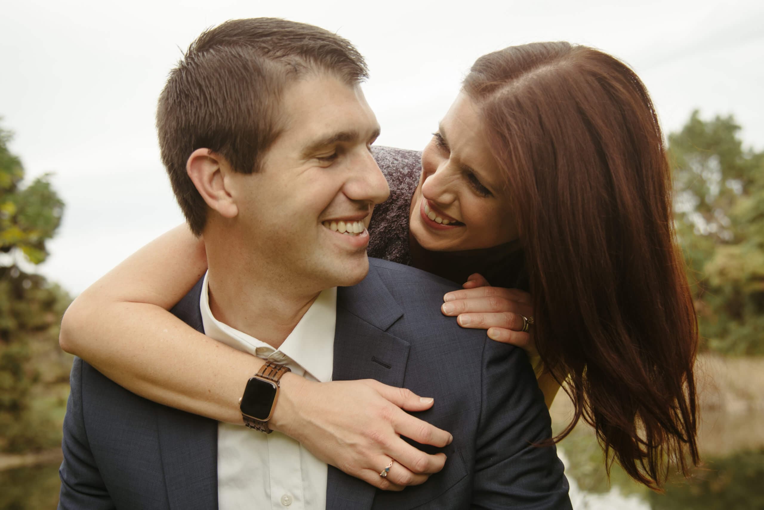 Man and woman smiling at each other intimately, with the woman's arms around the man's shoulder