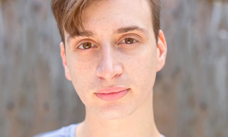 Young man with a neutral expression against a wooden background