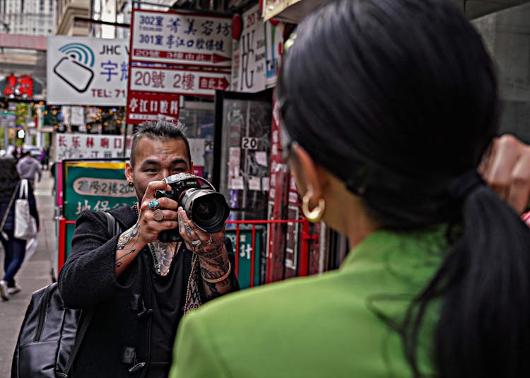 A photographer taking a picture of a person in a bustling urban street.