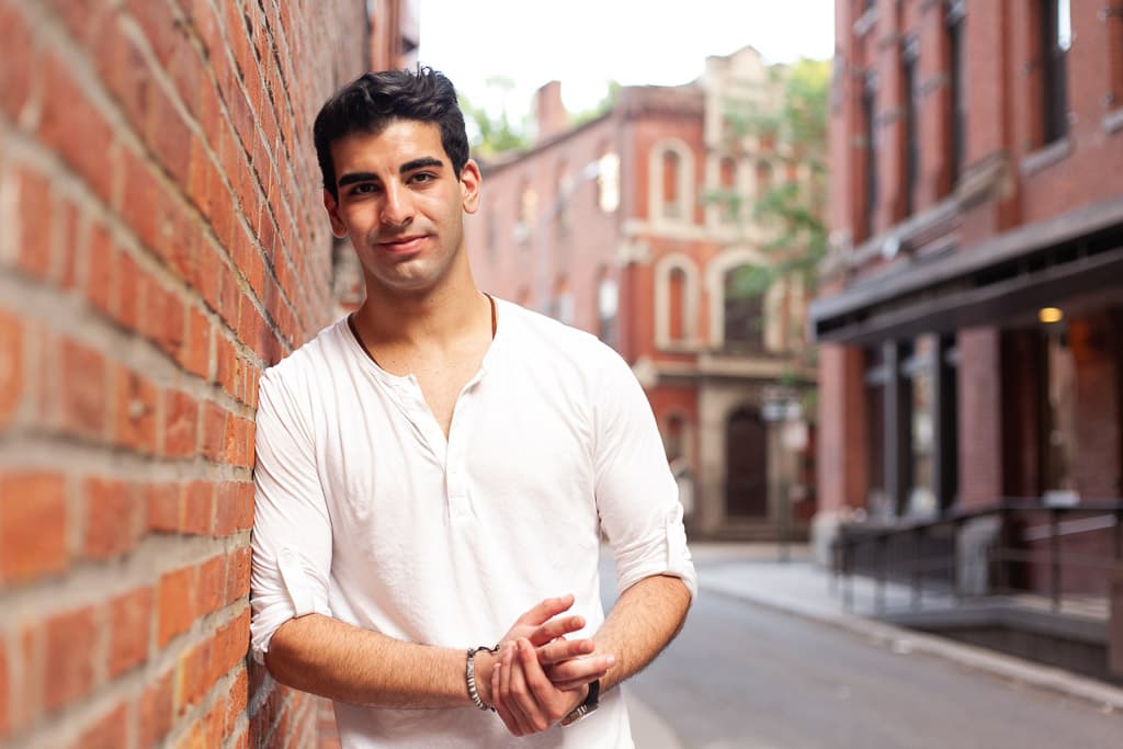 Man leaning against a brick wall on an urban street.