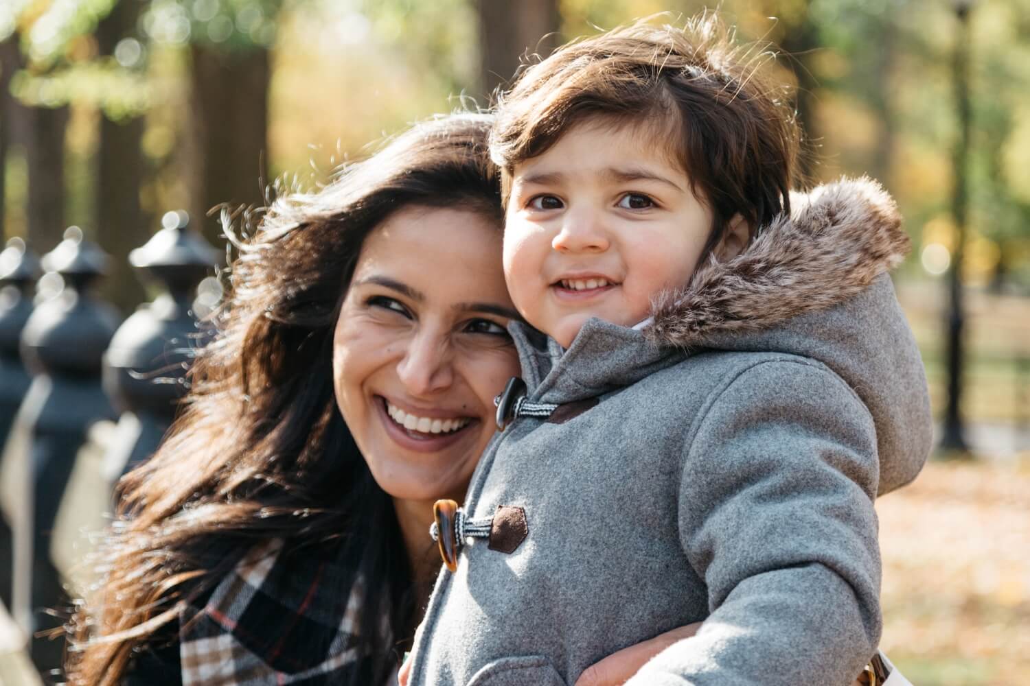 A smiling woman holding a child outdoors