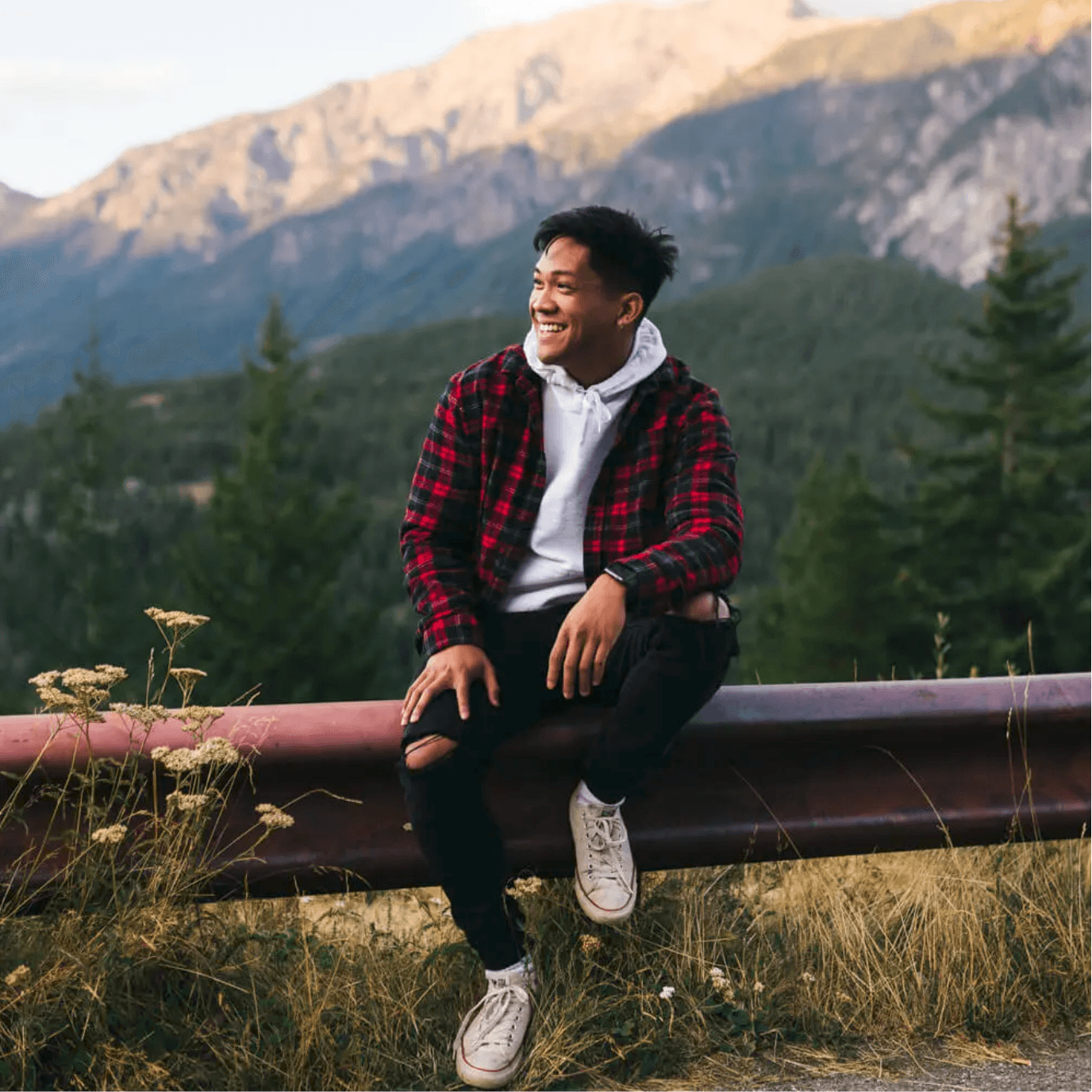 Man in plaid jacket smiling on a mountain road during free professional dating profile photo session with Shoott in Houston