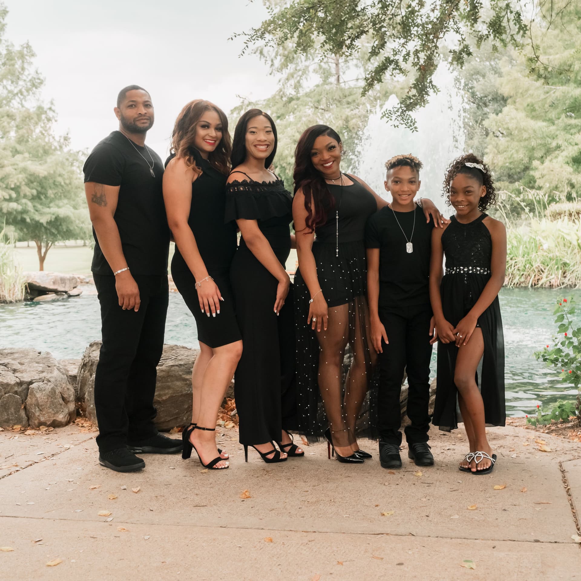 Family wearing matching outfits pose on a bridge for their free outdoor park photoshoot