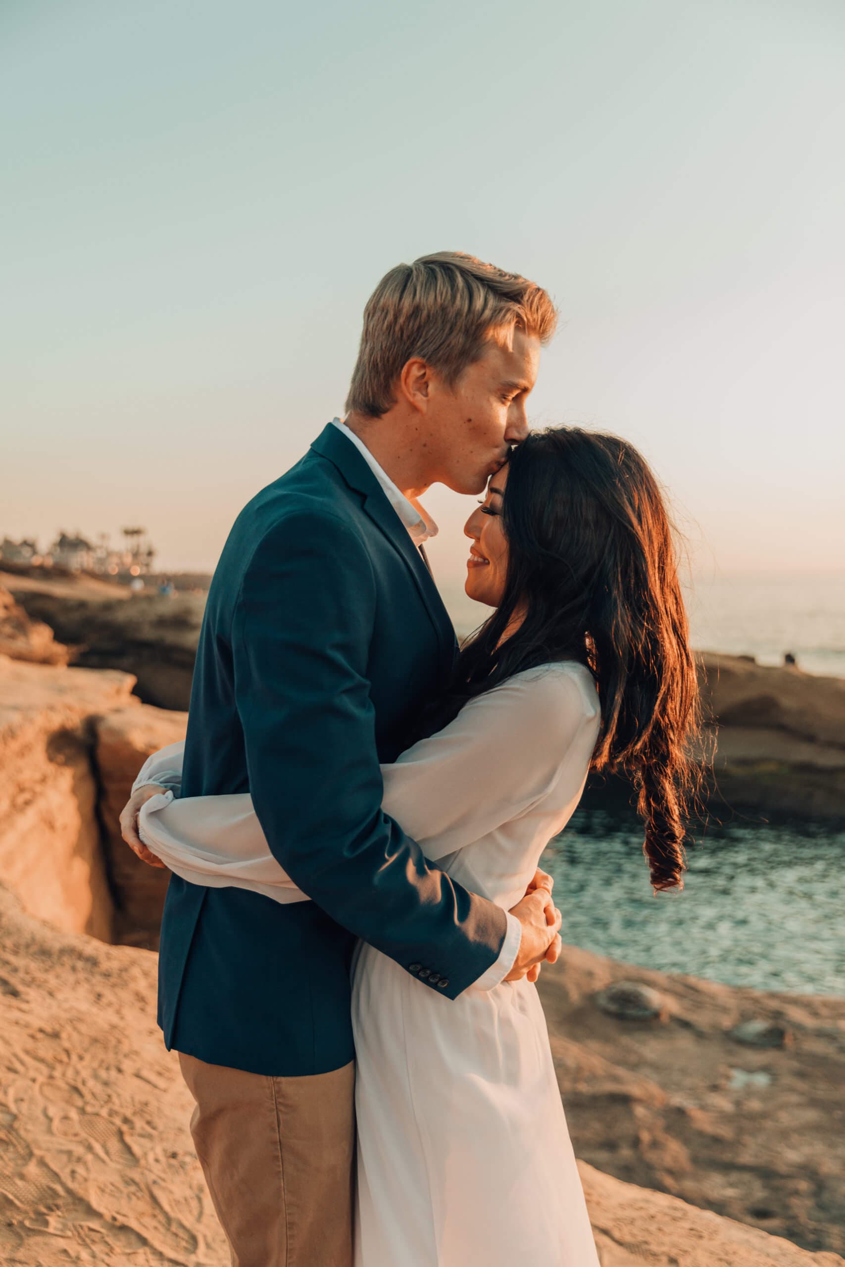 Couple embracing on a rocky beach at sunset